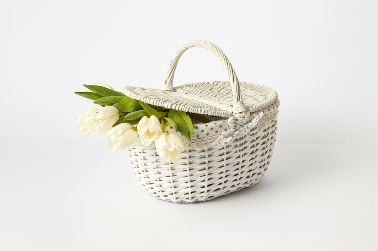 Elegant white wicker basket filled with fresh white tulips on a clean white background.